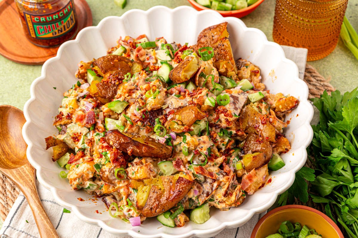 A white scalloped bowl with chili crisp smashed potato salad in it.