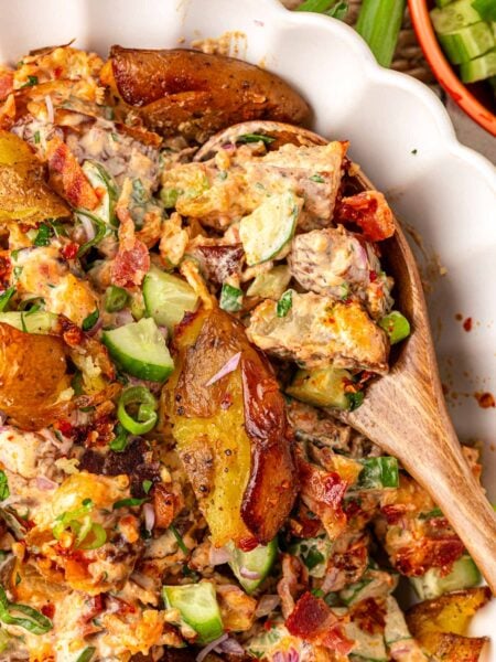 A wooden spoon in a white bowl filled with chili crisp smashed potato salad.
