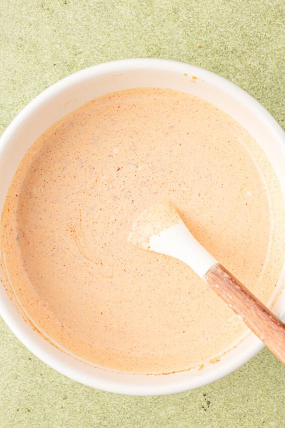 Creamy dressing for potato salad being mixed in a white bowl.