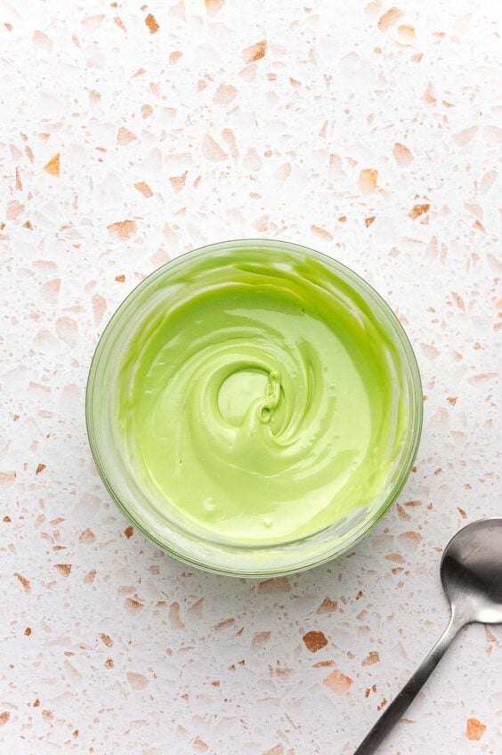 Green colored white chocolate in a small bowl.
