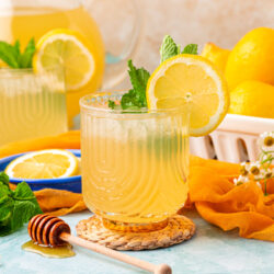 Two glasses of honey lemonade on a blue table.