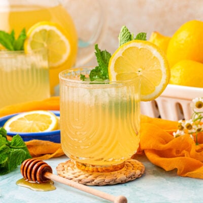 Two glasses of honey lemonade on a blue table.