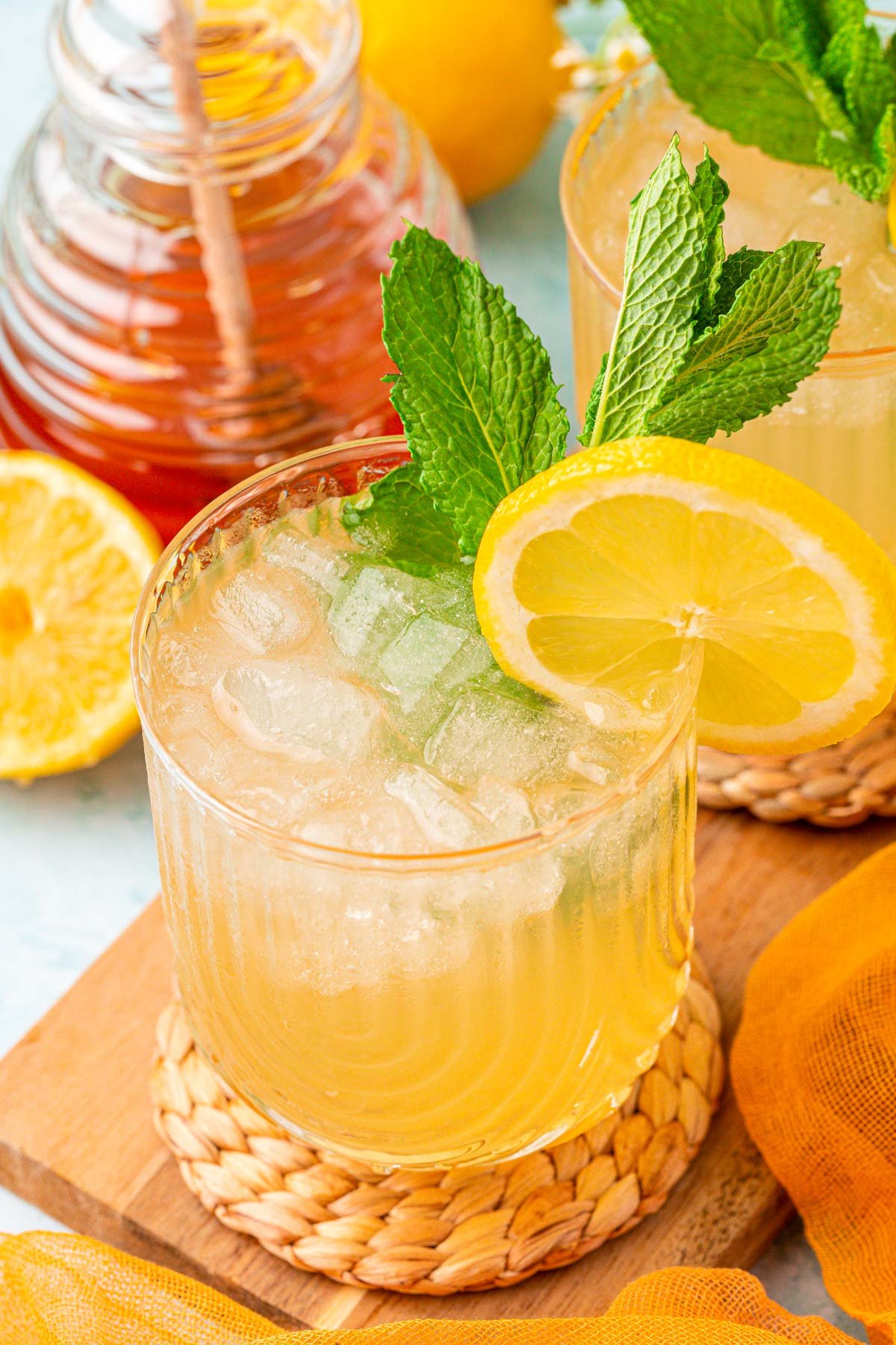 A glass of honey lemonade on a coaster on a wooden board.