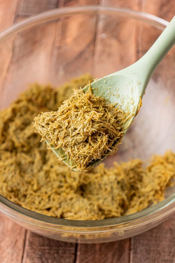 Pistachio coated katafi dough for Dubai desserts in a mixing bowl.