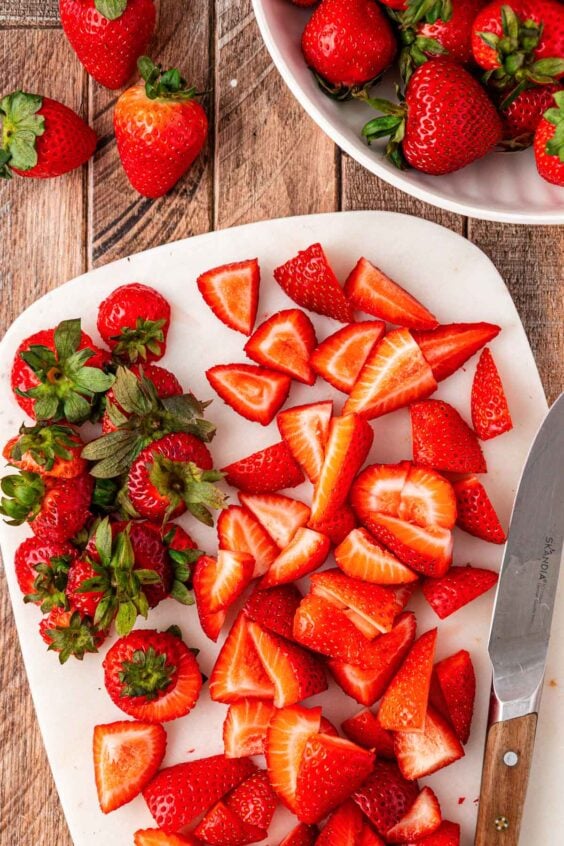 Chopped strawberries on a cutting board.