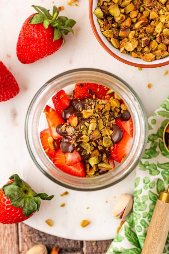 Melted chocolate drizzled over chopped strawberries in a jar.