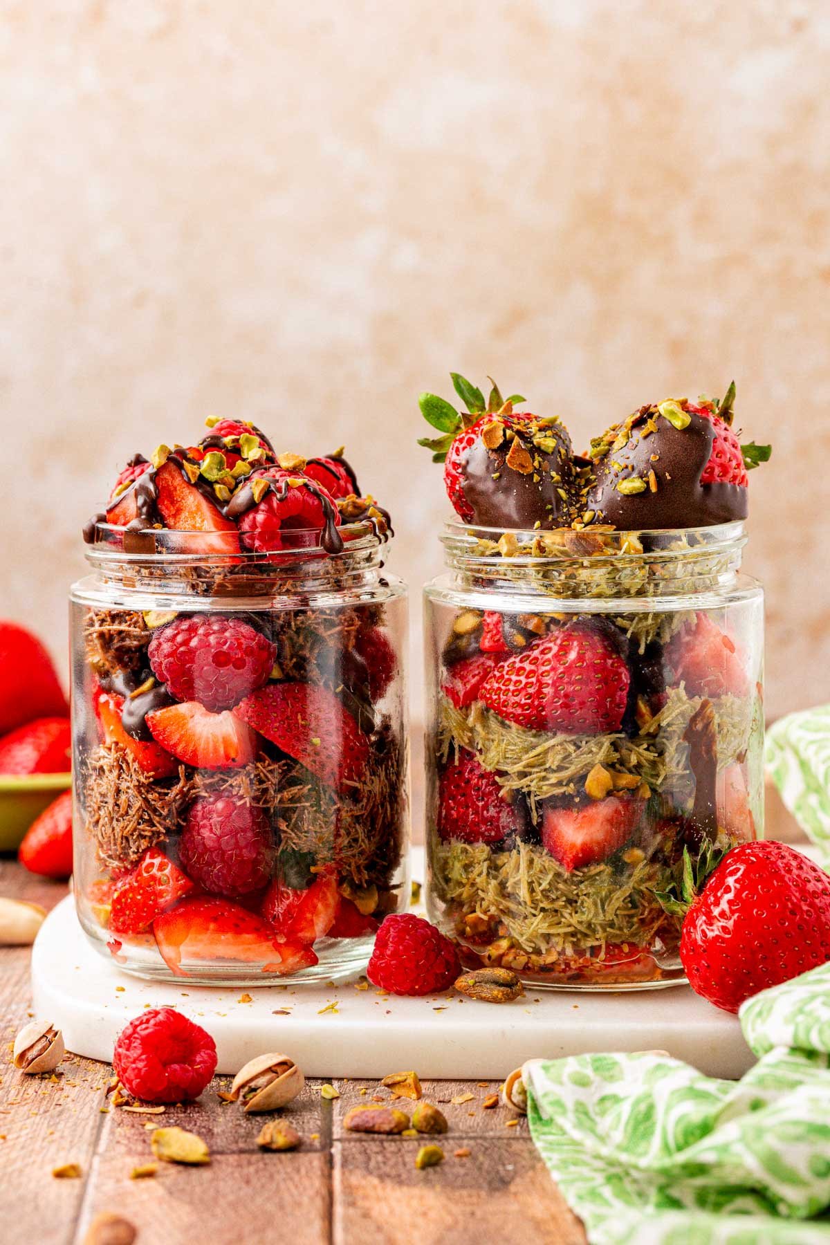 Dubai strawberry cups jars next to each other. One is made with pistachio cream and the other is made with Nutella.