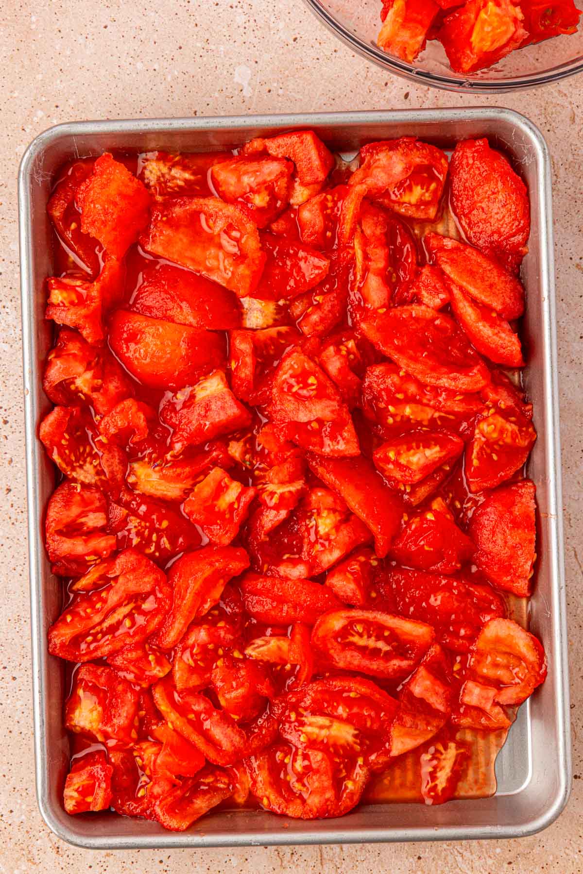 Chopped peeled tomatoes on a baking pan.