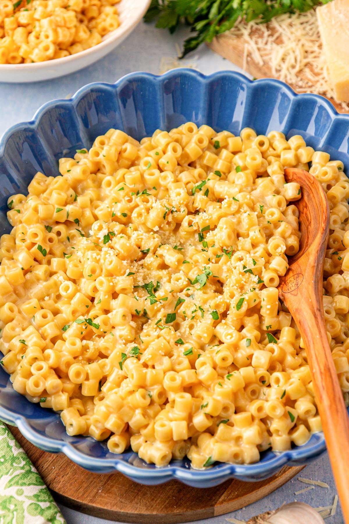 A blue bowl filled with creamy ditalini pasta and a wooden spoon.