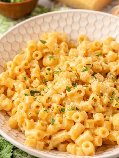 Close up of creamy ditalini pasta in a beige bowl.