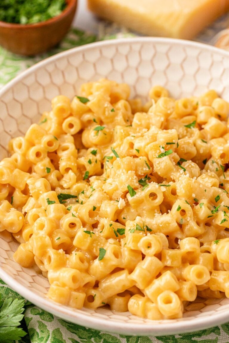 Close up of creamy ditalini pasta in a beige bowl.