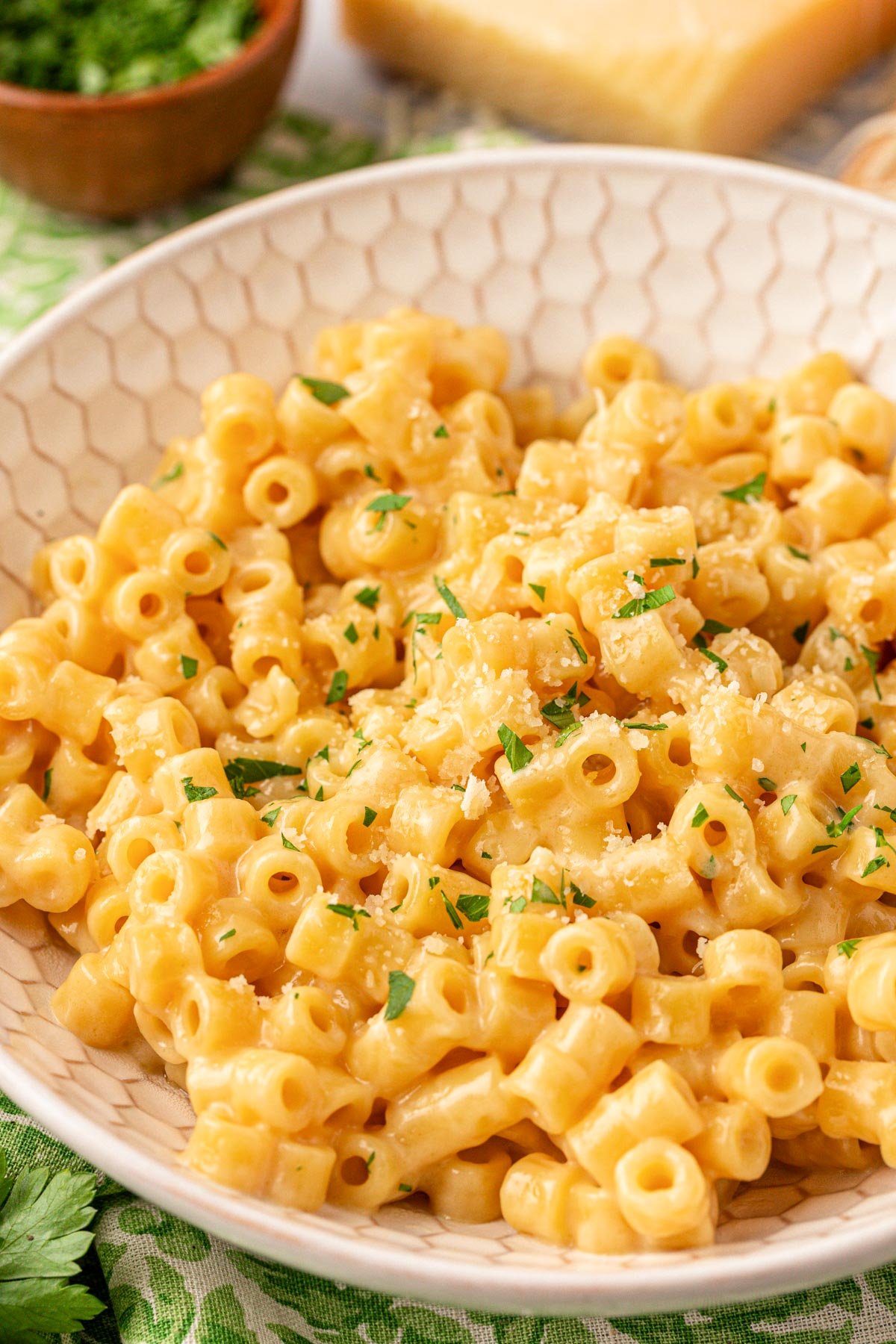Close up of creamy ditalini pasta in a beige bowl.