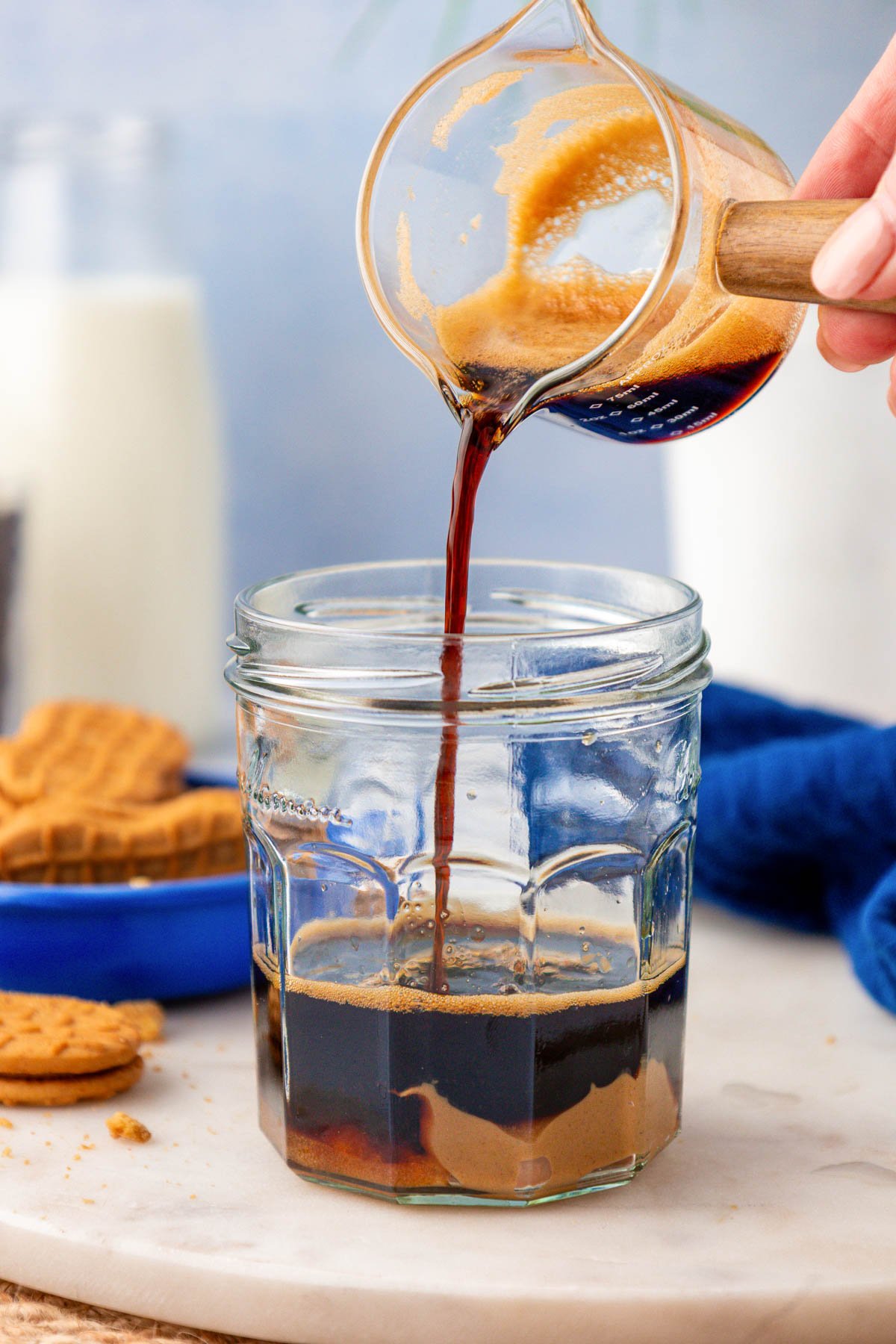 Espresso being poured into a jar with brown sugar and peanut butter.