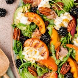 Close up of a burrata and peach salad on a plate.