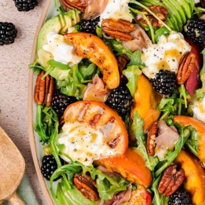 Close up of a burrata and peach salad on a plate.