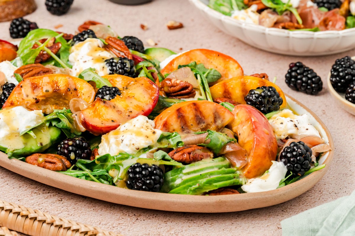 A plate filled with burrata peach salad.