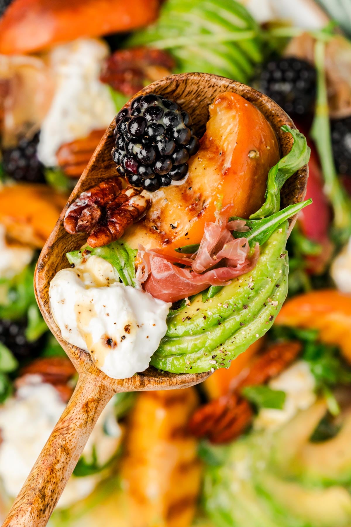 A serving spoon of burrata peach salad.