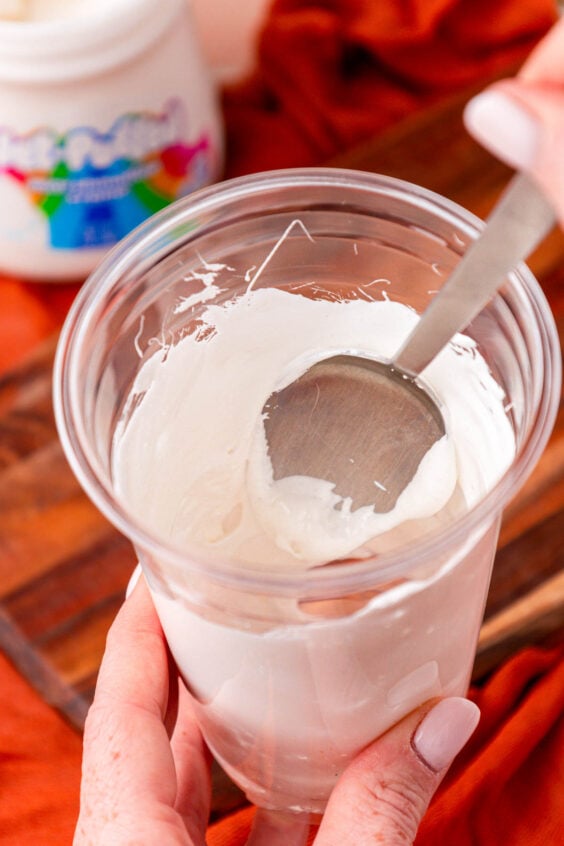 Fluff being spread around the inside of a plastic coffee cup.