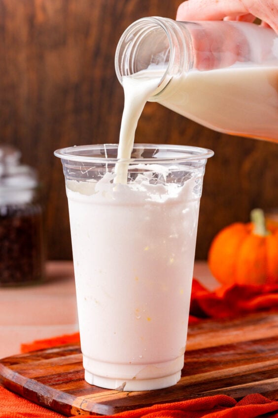 Milk being poured into a cup with marshmallow fluff and ice.
