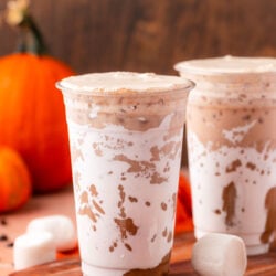 Fluffy pumpkin iced latte on a table with orange linens.