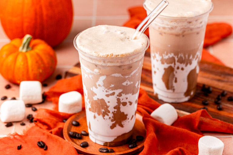 Close up of two cups of pumpkin nutella iced coffees on an orange table.