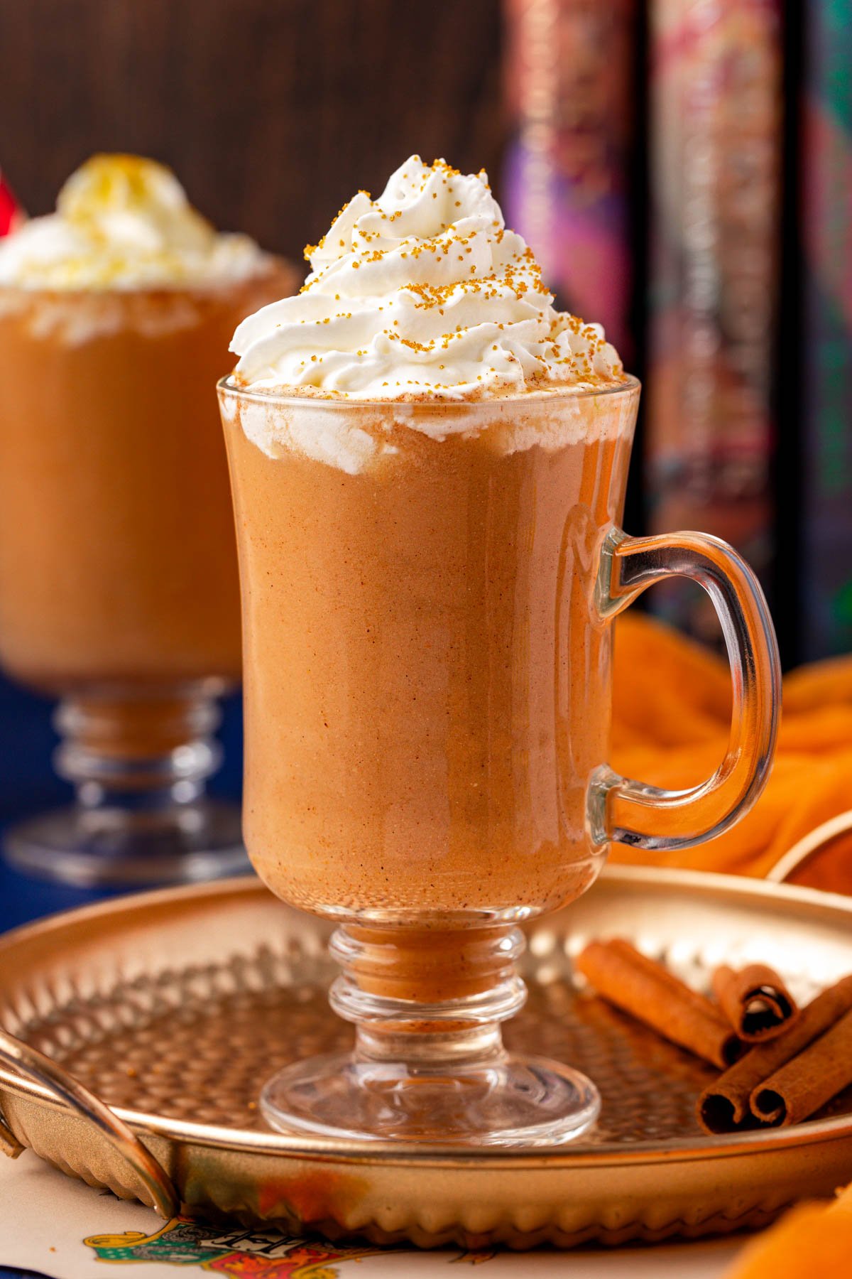Close up of a glass mug filled with pumpkin juice and topped with whipped cream.