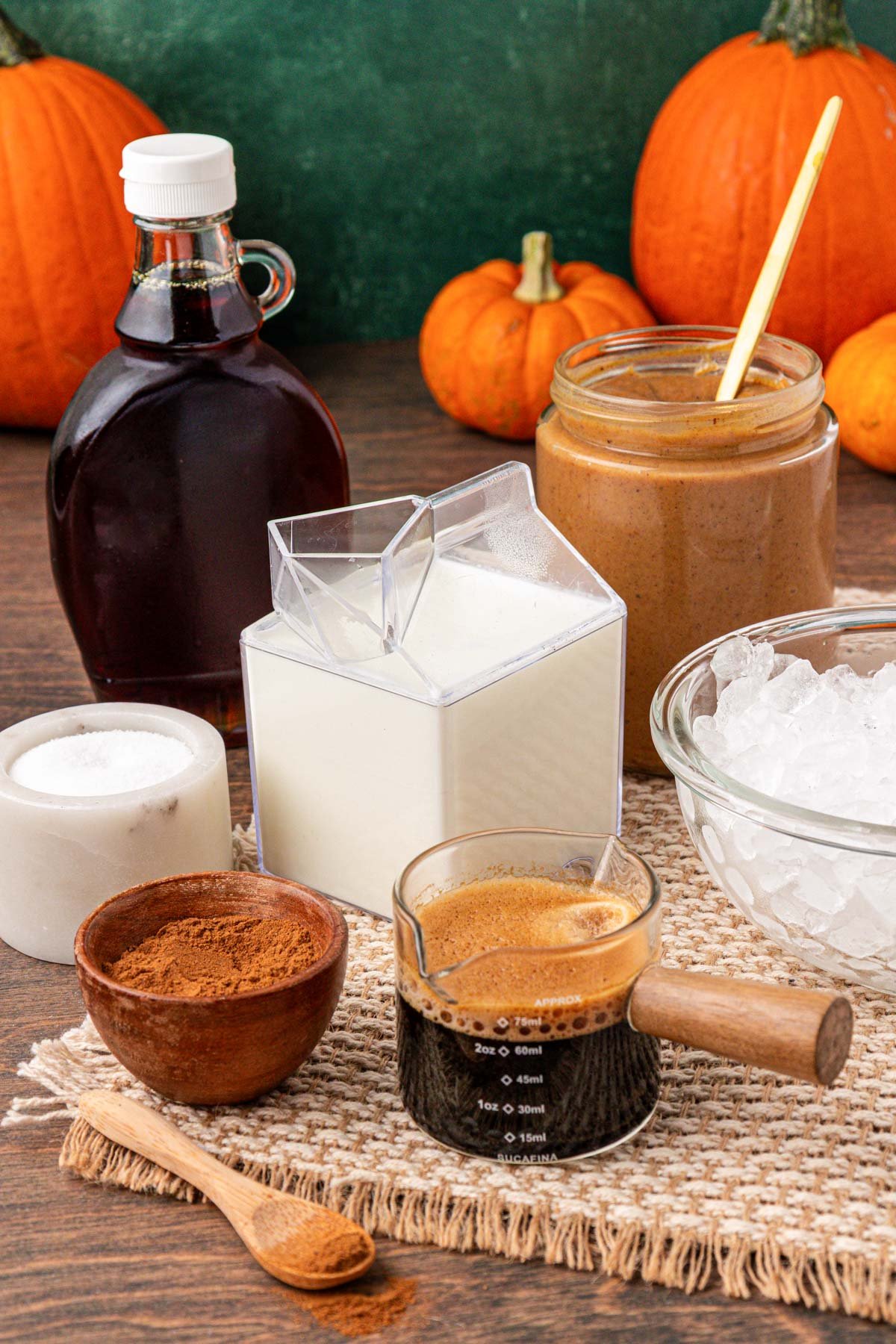 Ingredients to make an iced pumpkin spiced latte on a table.