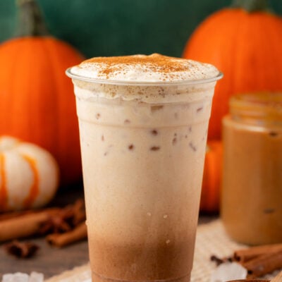 Homemade Iced Pumpkin Spice Latte in a tall plastic cup on a table.