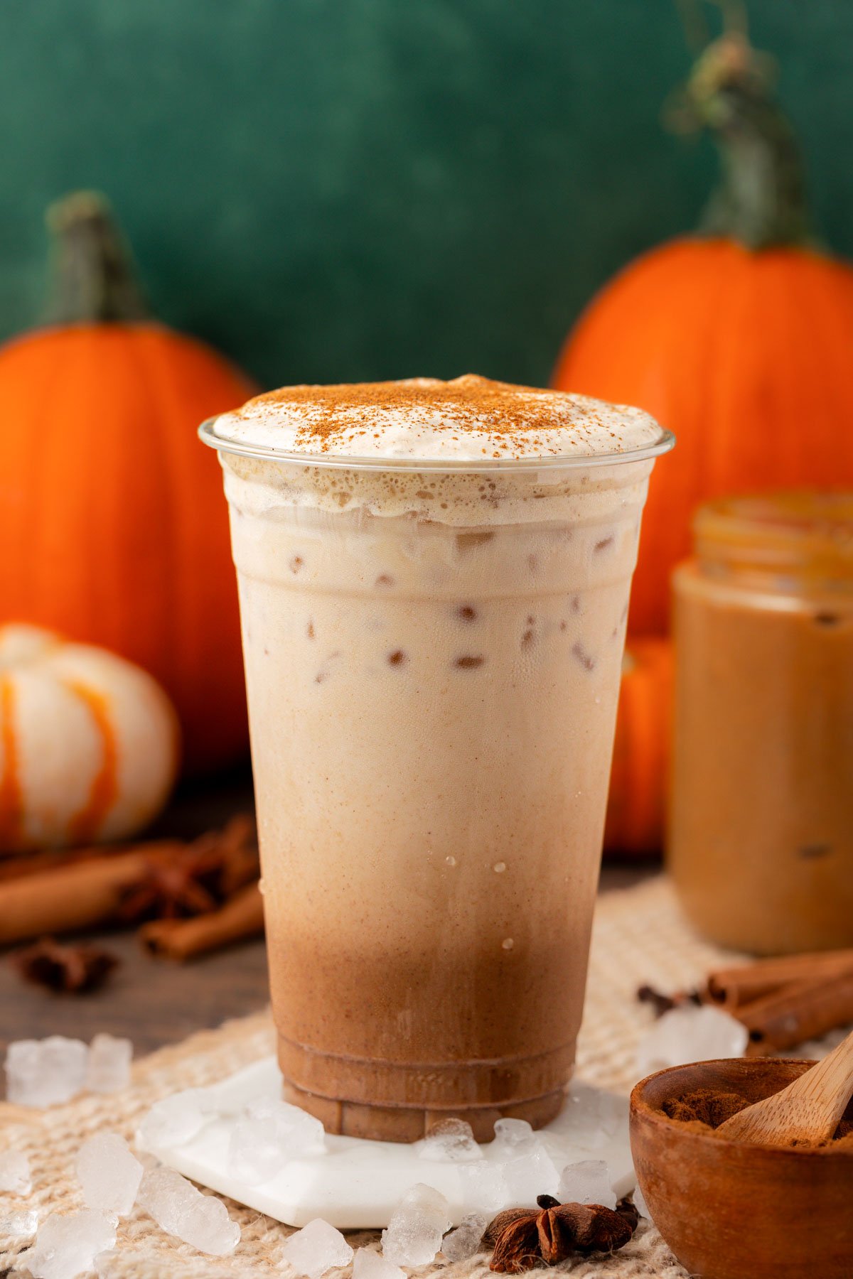 Homemade Iced Pumpkin Spice Latte in a tall plastic cup on a table.