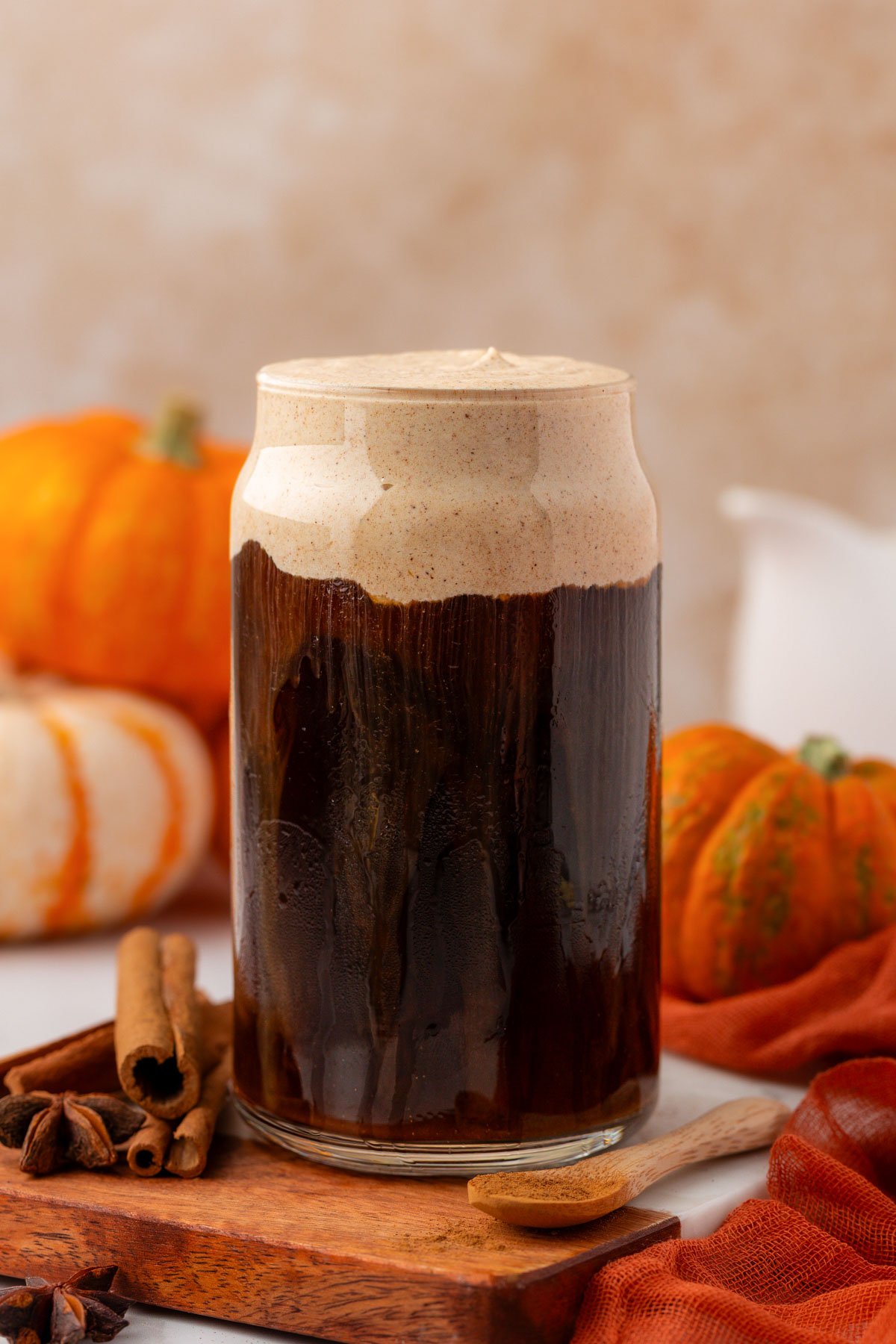 A glass of cold brew topped with pumpkin cold foam on a wooden tray.