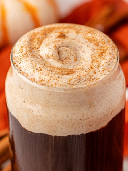 Close up of a glass of cold brew topped with pumpkin cold foam and pumpkin spice on top.