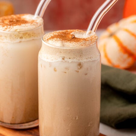 Two glasses of pumpkin chai latte on a table.