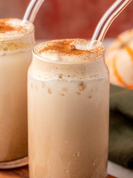 Two glasses of pumpkin chai latte on a table.