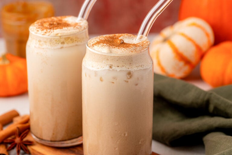 Two glasses of pumpkin chai latte on a table.