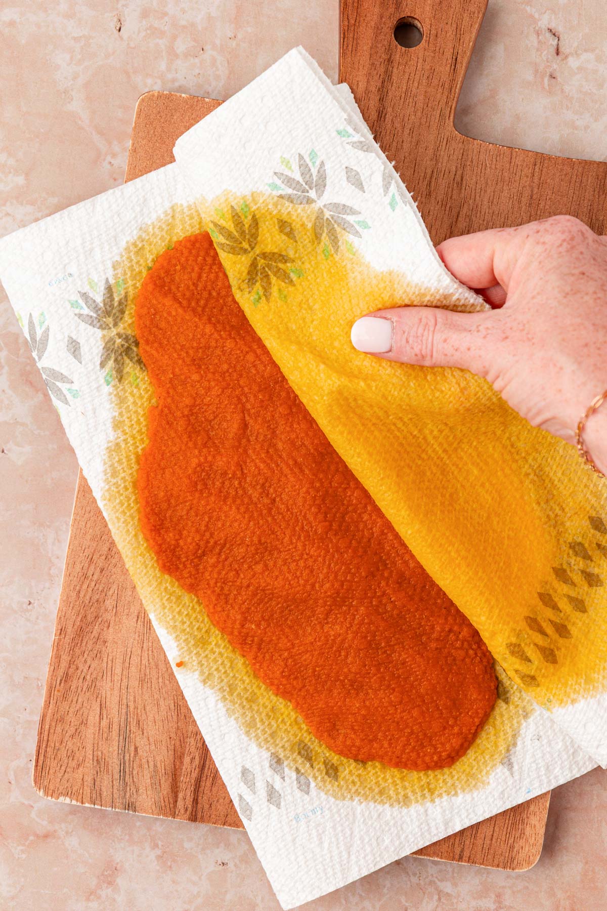 Pumpkin puree being patted with paper towels to reduce moisture.
