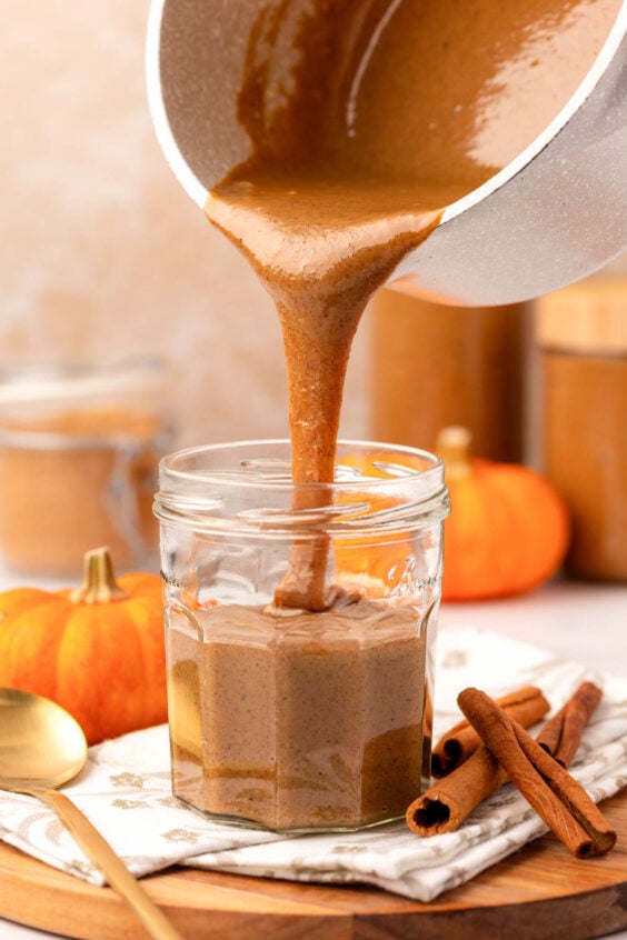 Pumpkin Spice Sauce being poured into a jar on a table.