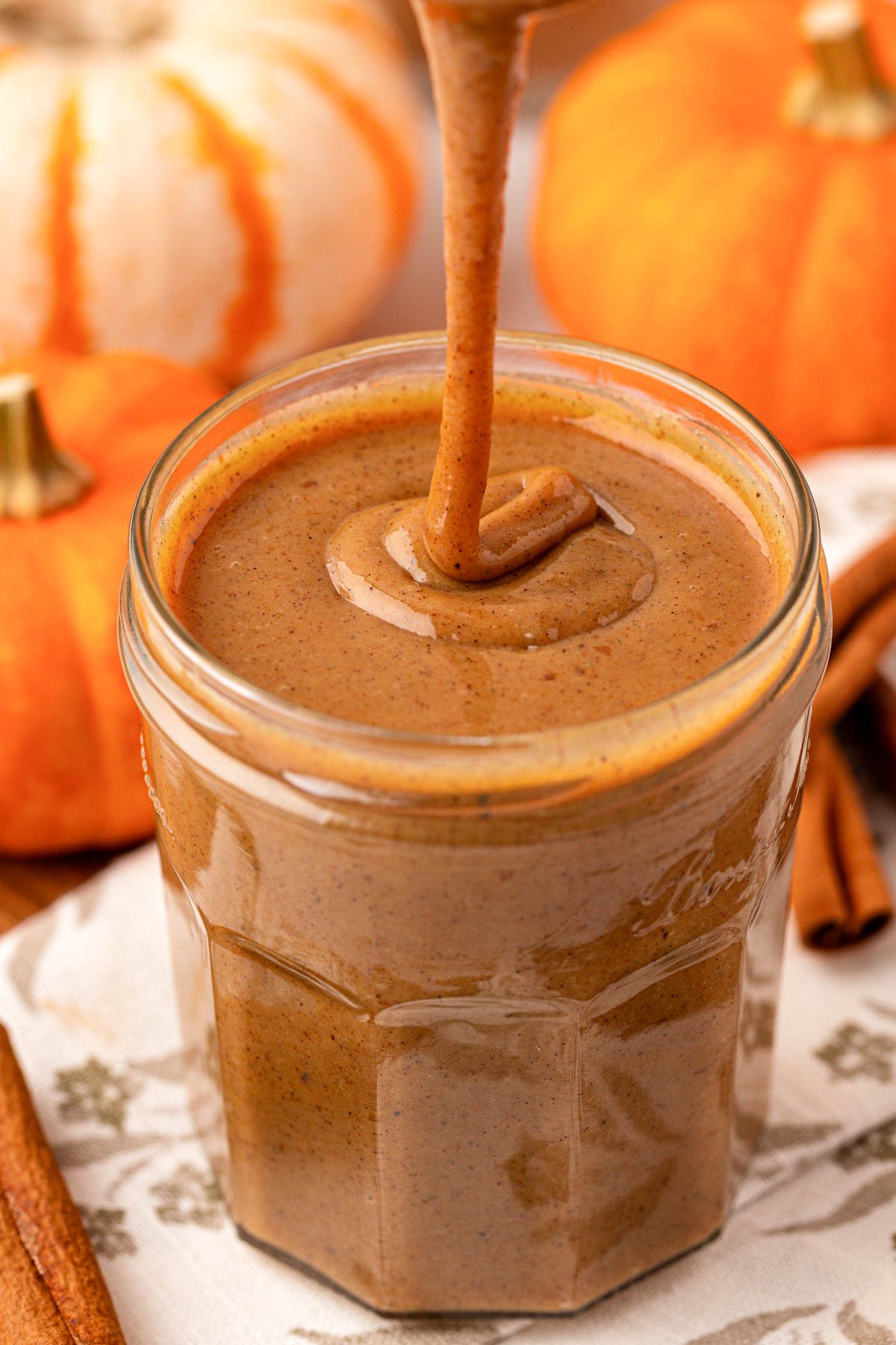 Pumpkin Spice Sauce being drizzled into a jar.