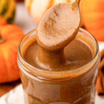 Close up of a jar filled with pumpkin spice sauce with a spoon pulling out of it.