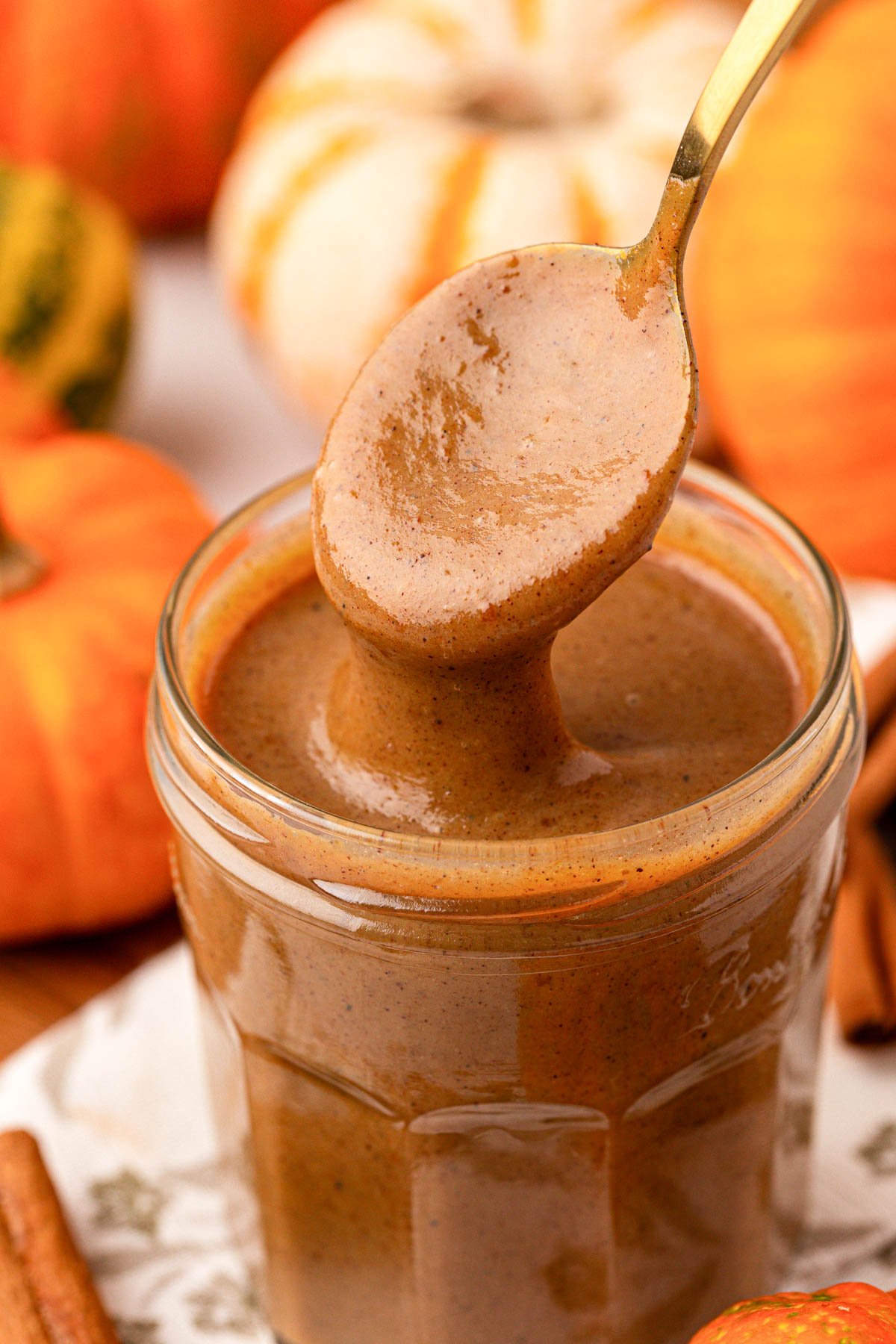Close up of a jar filled with pumpkin spice sauce with a spoon pulling out of it.