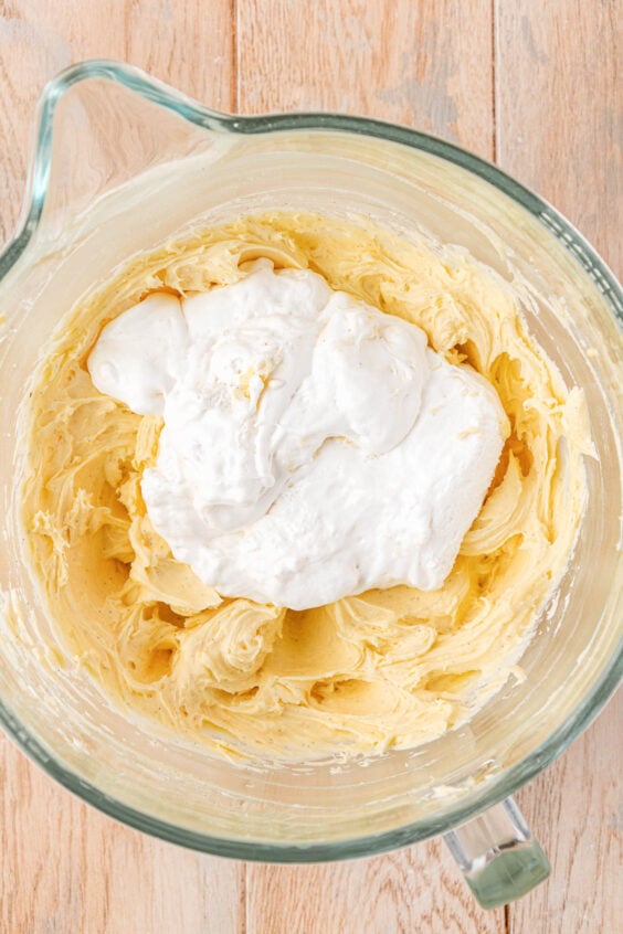Marshmallow fluff being added to a mixing bowl to make frosting.