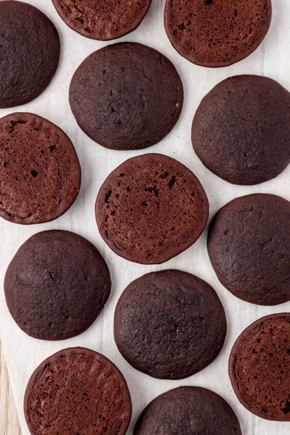 Chocolate cakes for whoopie pies on a parchment-lined pan.