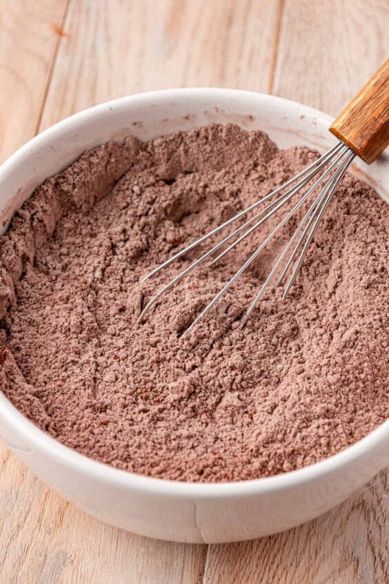 Dry chocolate cake ingredients being whisked in a bowl.