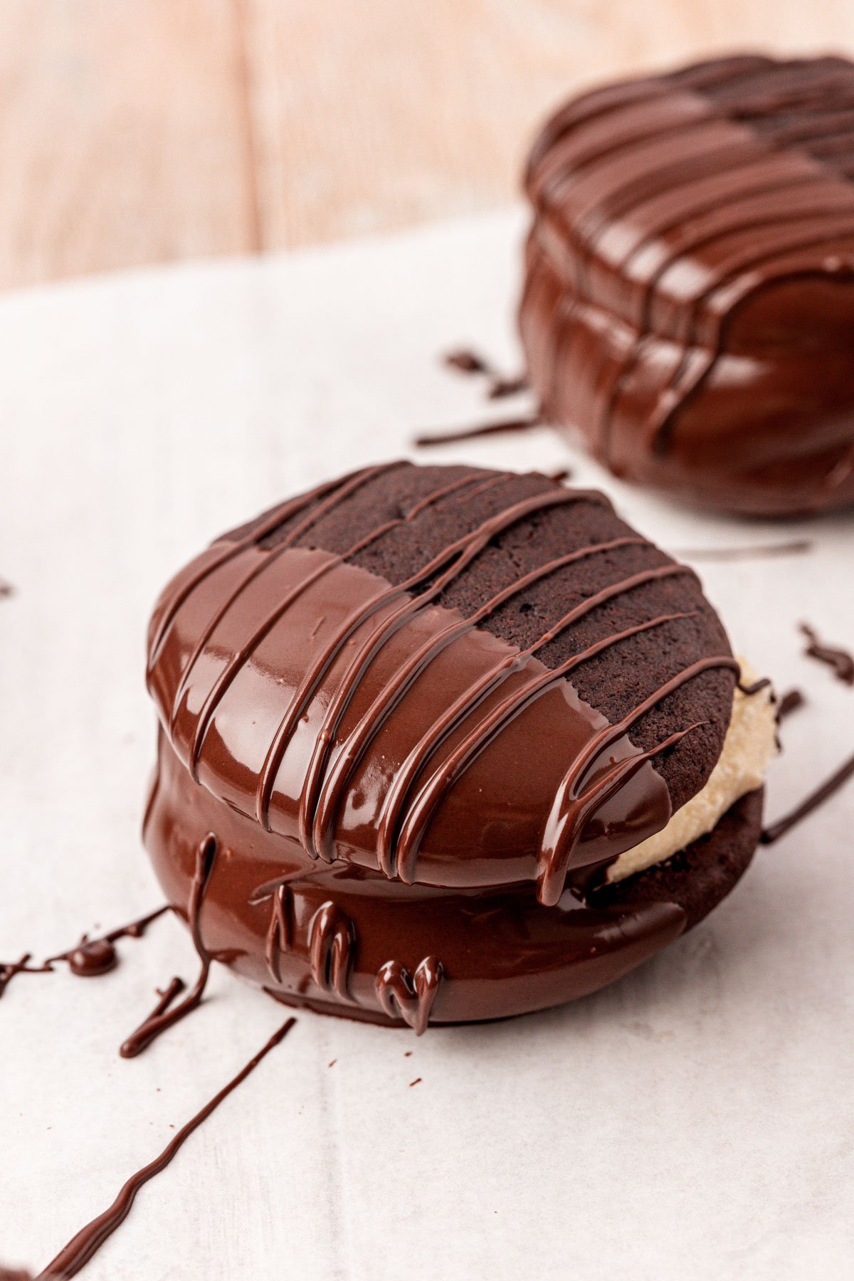 Whoopie pies dipped half way in chocolate on a piece of parchment paper.