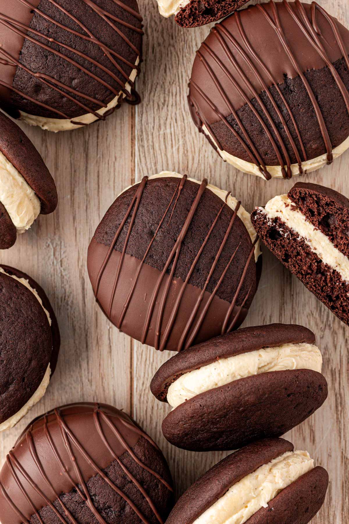 Whoopies pies half dipped in chocolate on a wooden table.