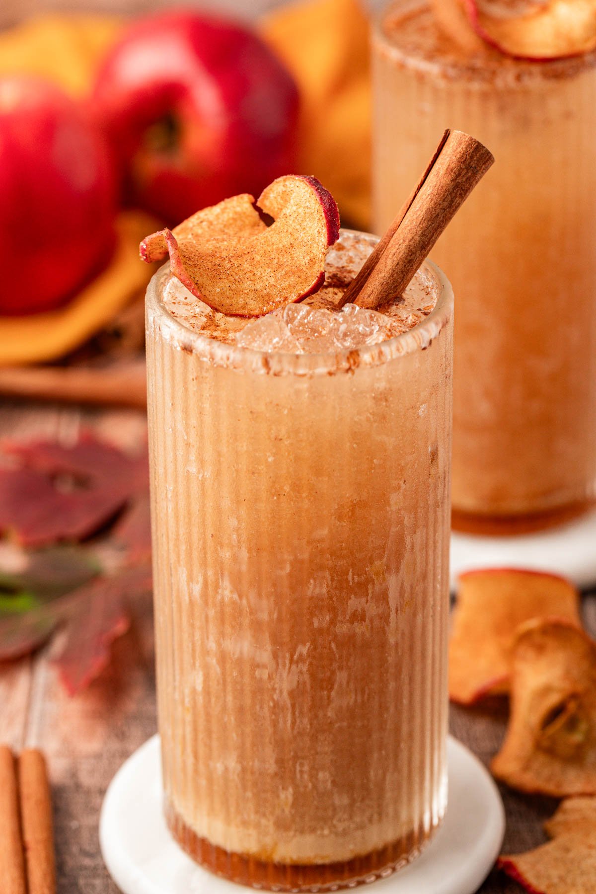 Close up of a tall glass filled with an apple refresher drink and garnished with a cinnamon stick.