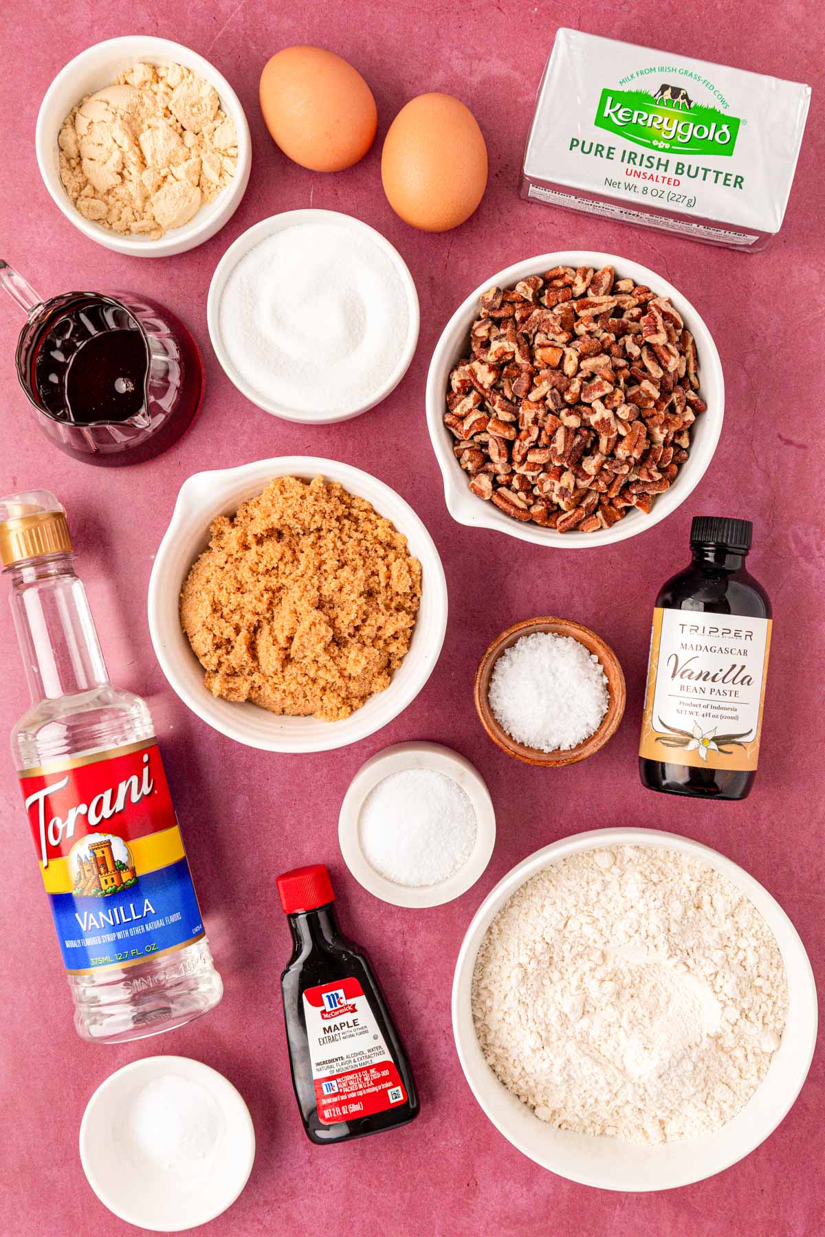 Ingredients to make maple pecan cookies on a maroon table.