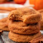 Close up of a stack of three pumpkin snickerdoodle cookies on a baking pan.