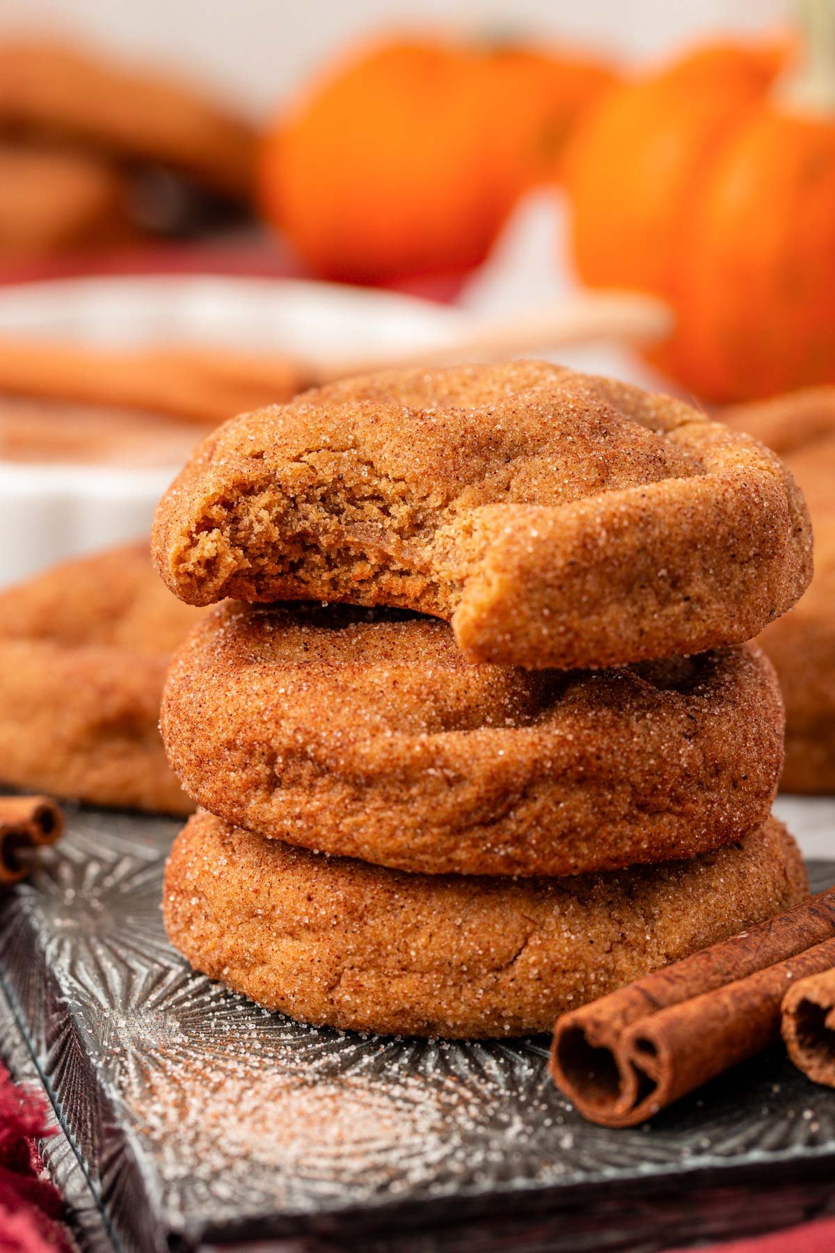 Close up of a stack of three pumpkin snickerdoodle cookies on a baking pan.
