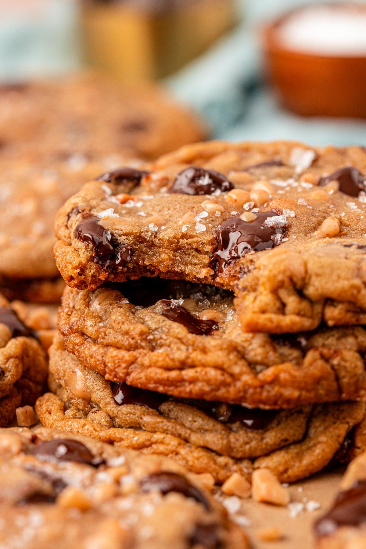 Close up photo of a stack of three toffee chocolate chip cookies, the top one is missing a bite.