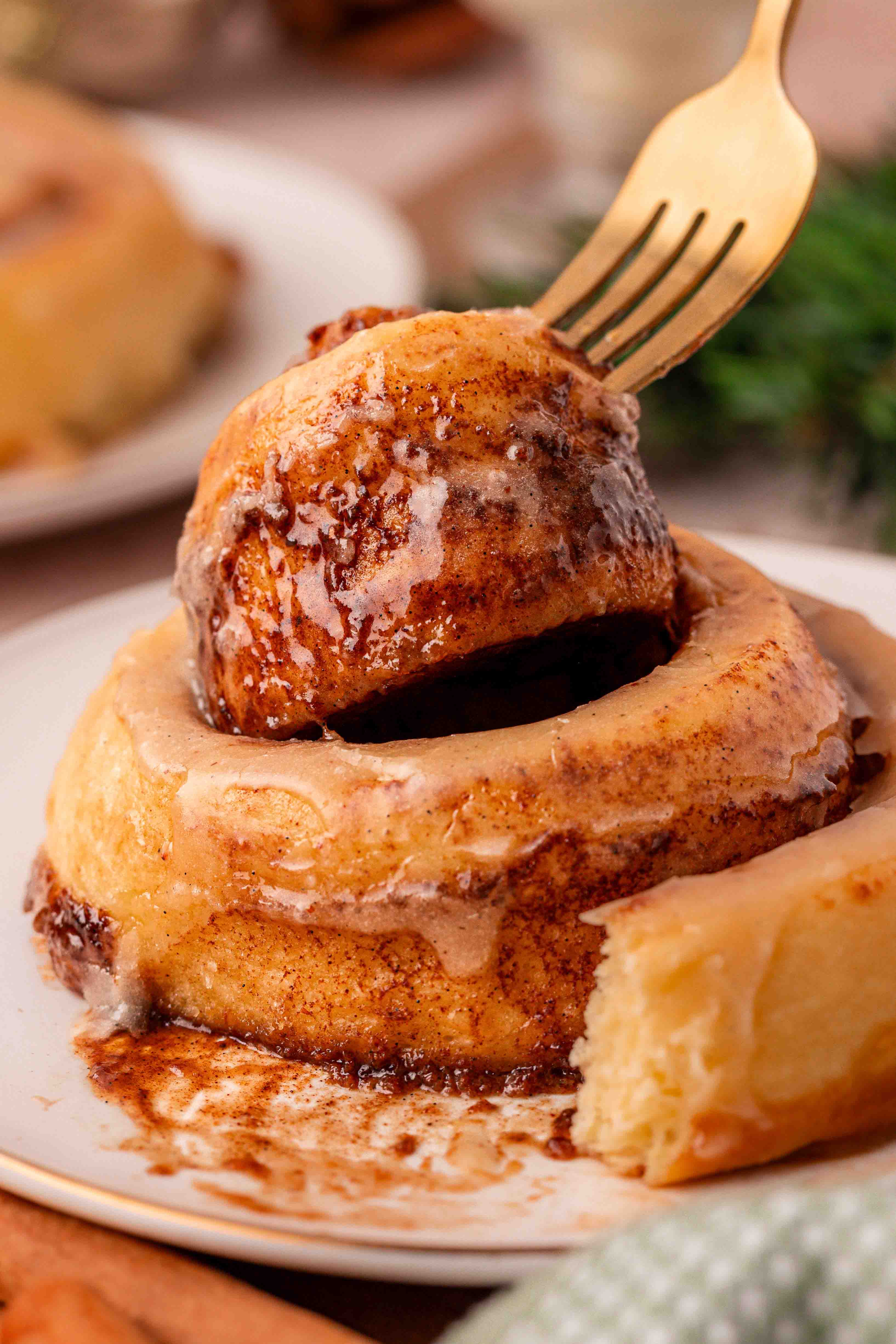 A fork pulling the center out of a cinnamon roll.